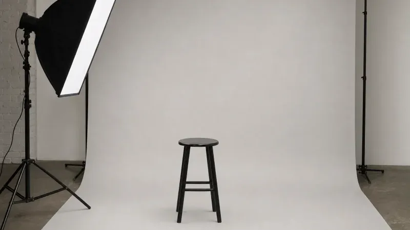 Studio fotograficzne z jasnym tłem, stołkiem i lampą do zdjęć dokumentowych